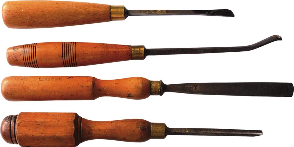 Four vintage wooden-handled chisels arranged horizontally.