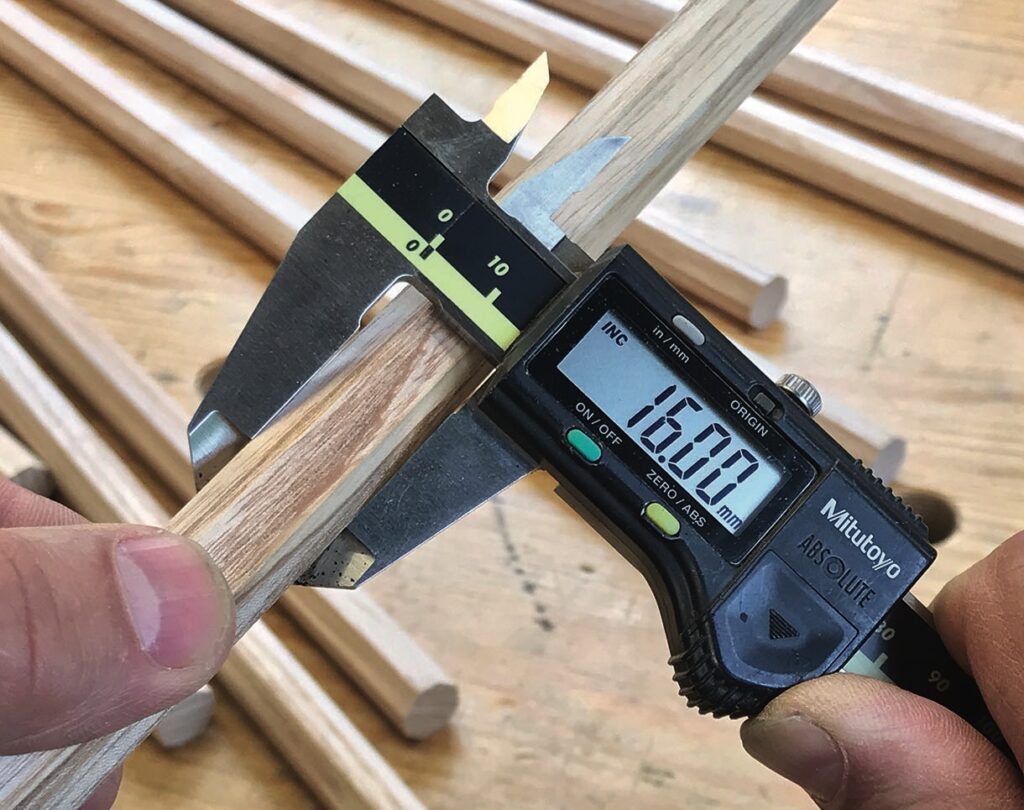 Digital caliper measuring wooden dowel diameter.