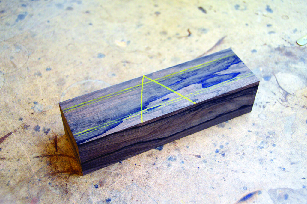Rectangular wood block with blue and yellow markings.