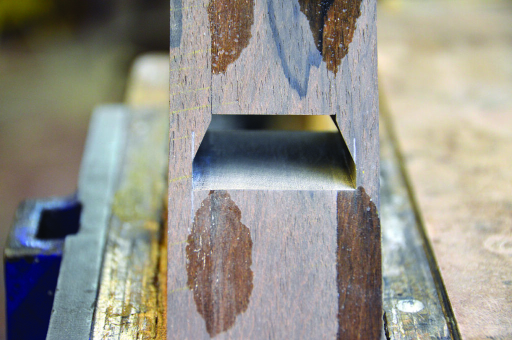 Wooden dovetail joint close-up in workshop setting.