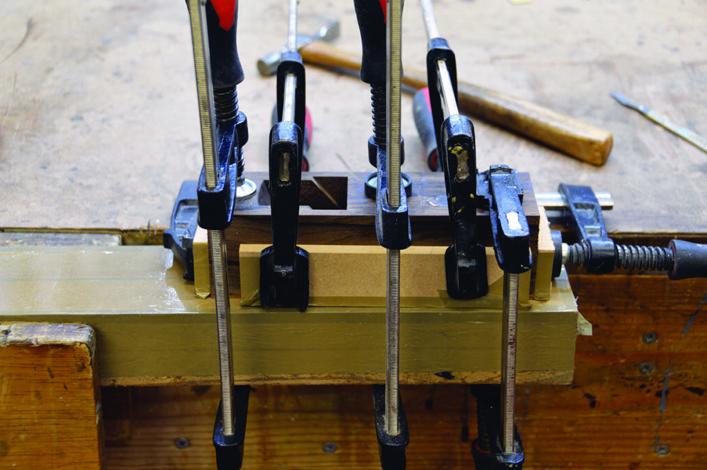 Wood piece clamped on workbench for woodworking.