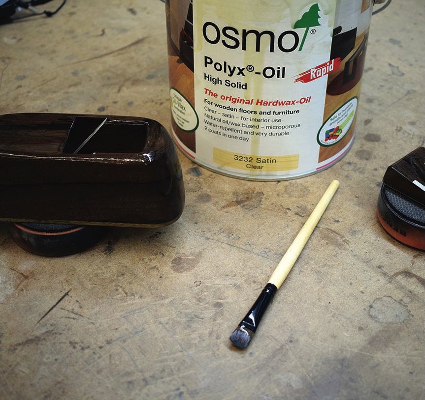 Osmo Polyx-Oil with brush on wooden table.