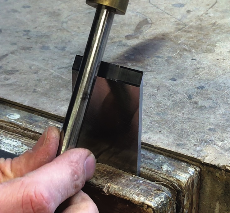 Hand sharpening woodworking chisel on bench.