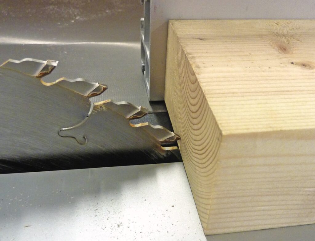 Saw blade cutting a thick wooden beam