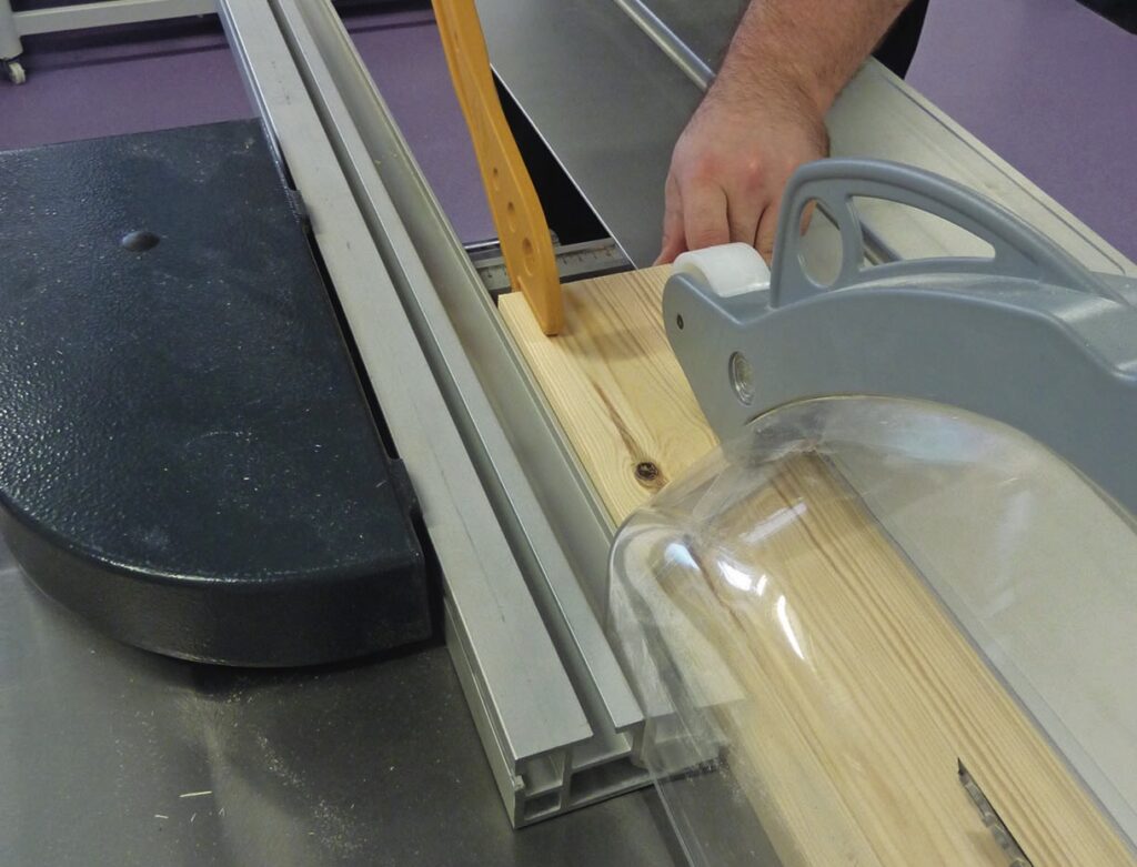 Person cutting a wooden plank with a table saw
