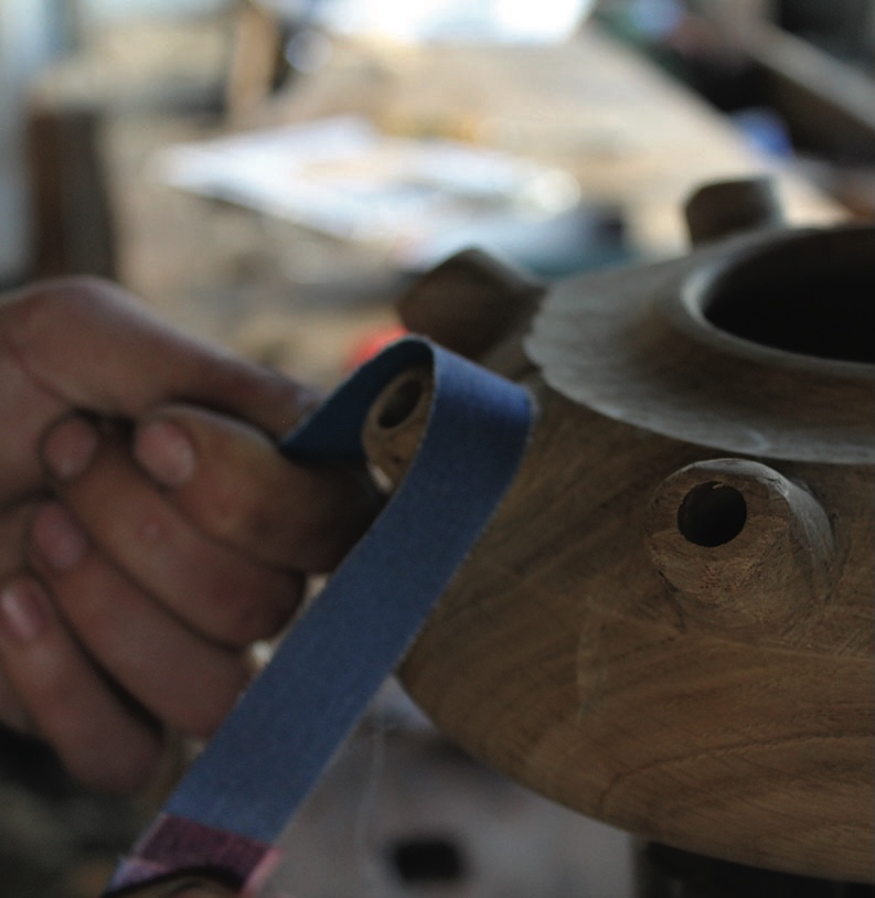 Hand sanding wooden object with sandpaper