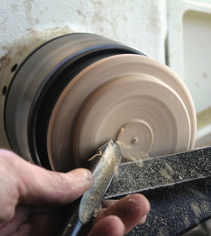 Woodturning on a lathe with a chisel tool.