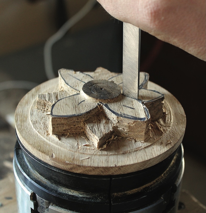 Wooden flower carving in progress with chisel.