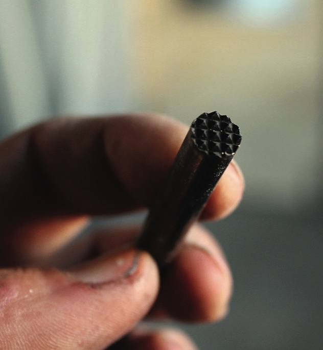 Hand holding metal stamping tool close-up