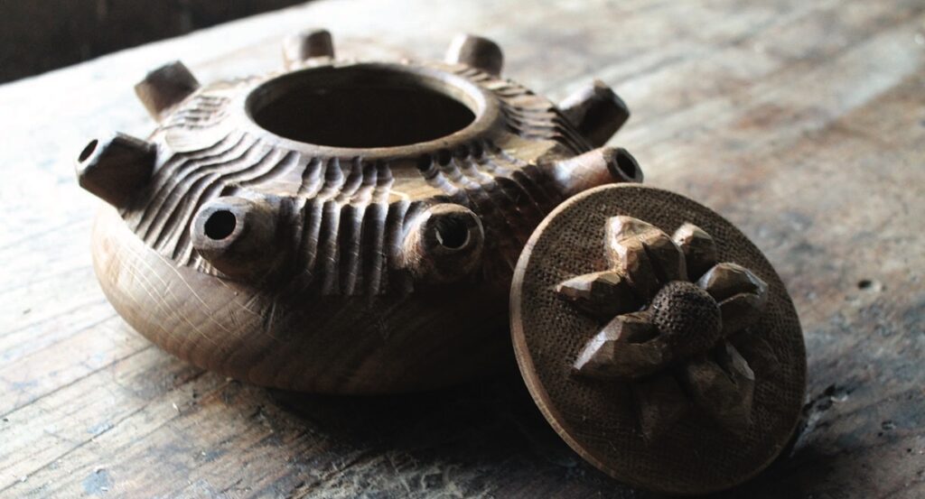 Wooden sculpture with circular lid on table.