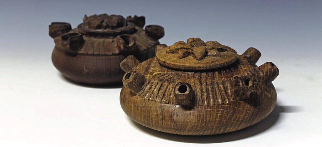 Two wooden carved pots with decorative lids.