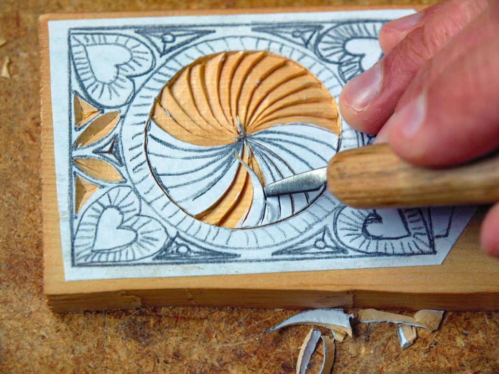 Intricate wood carving in progress with hand chisel.