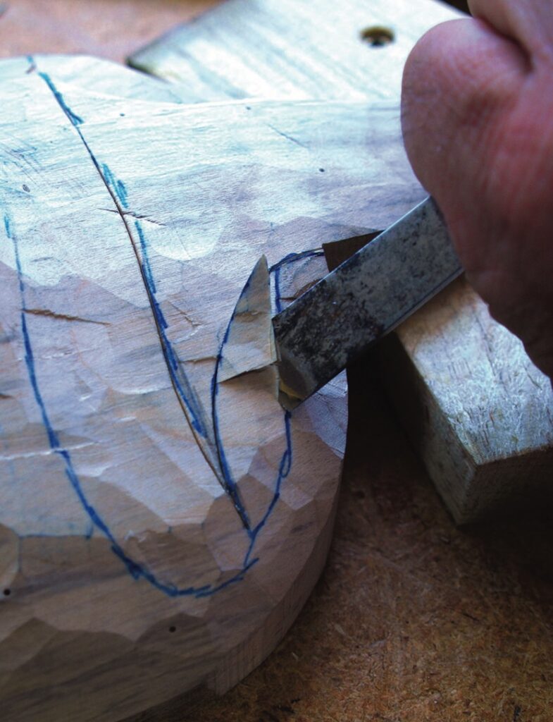 Craftsperson carving marked wooden form with a chisel