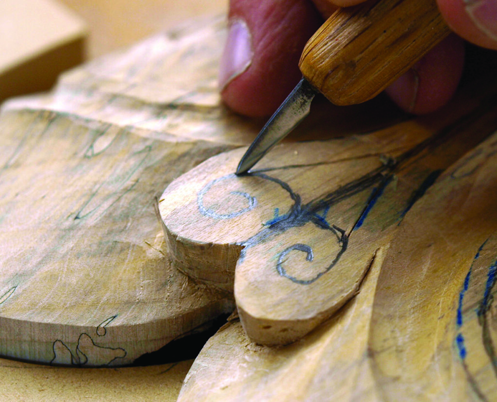 Craftsperson carving a wooden figurine with a chisel