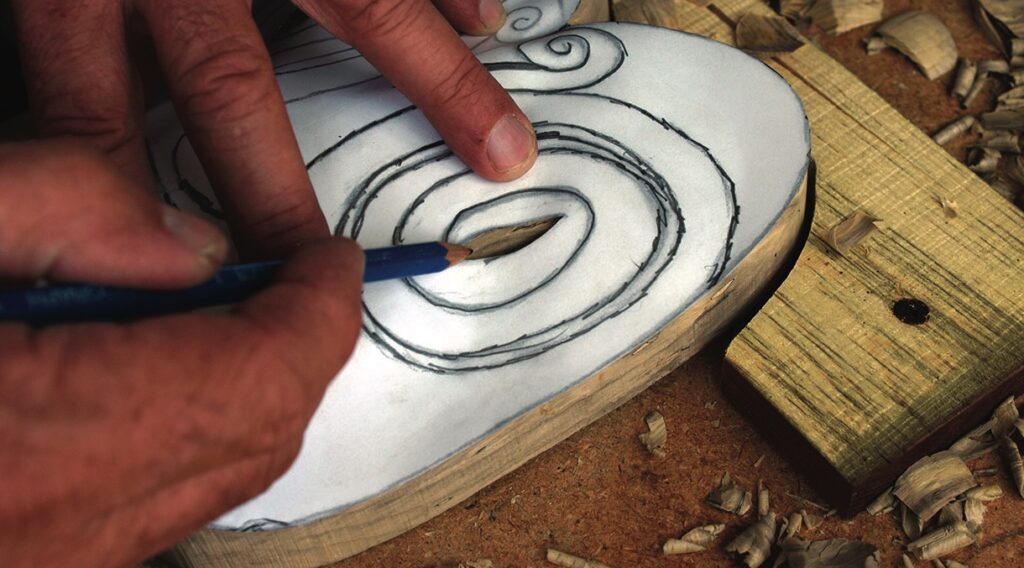Craftsperson tracing spiral template onto a wooden board