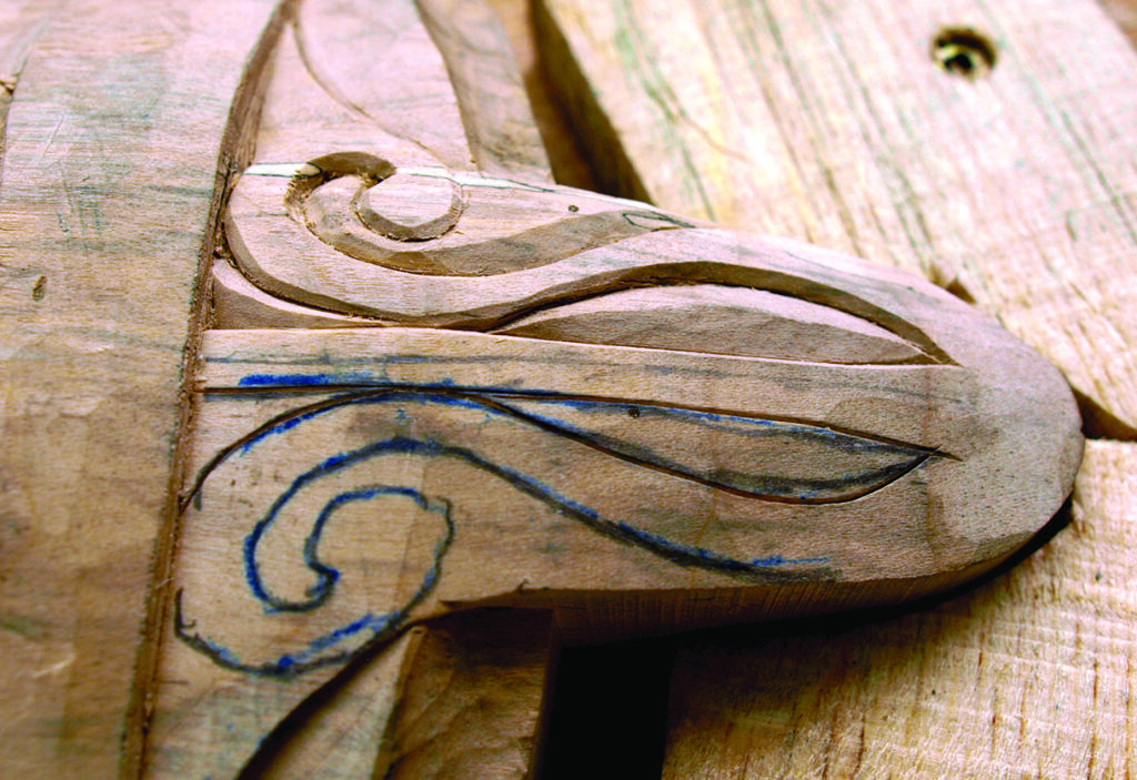 Carved wooden bird head with sketched design lines