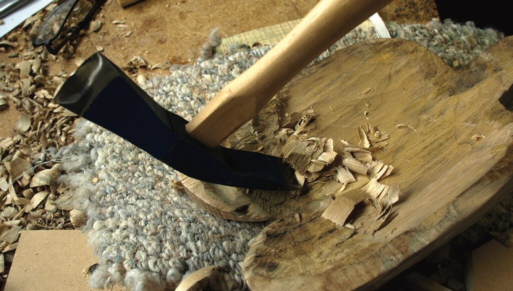 Adze carving wood on a log