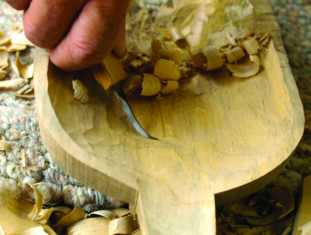 Hand carving a wooden spoon with a hooked knife