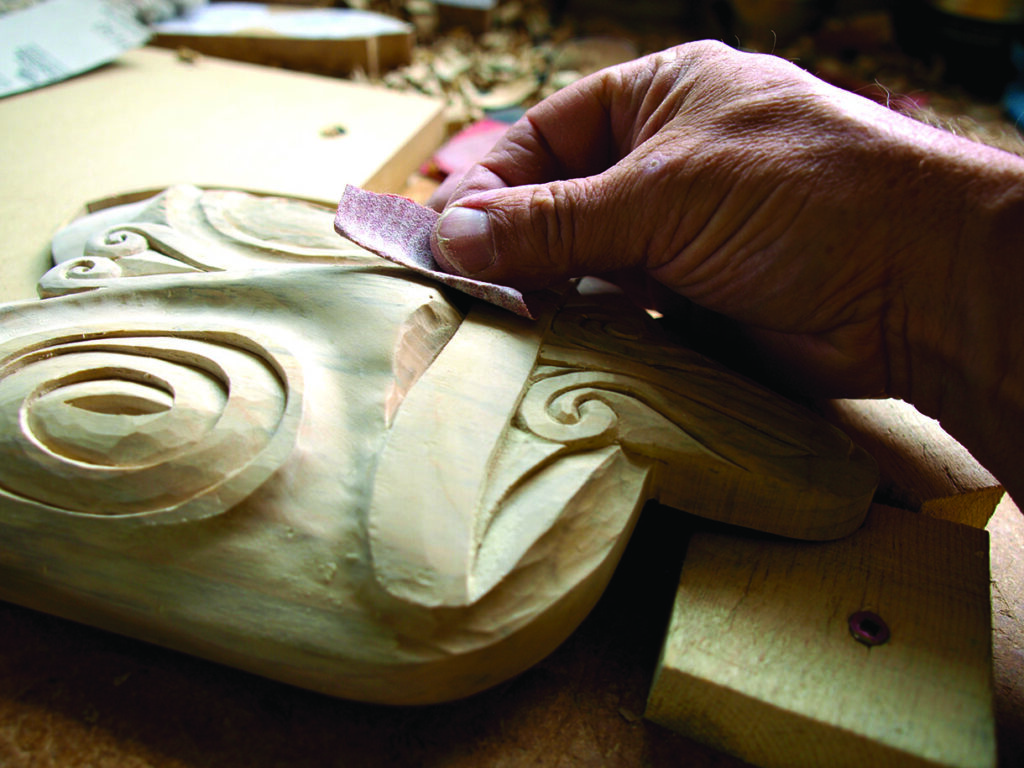 Craftsperson sanding a carved wooden ornament