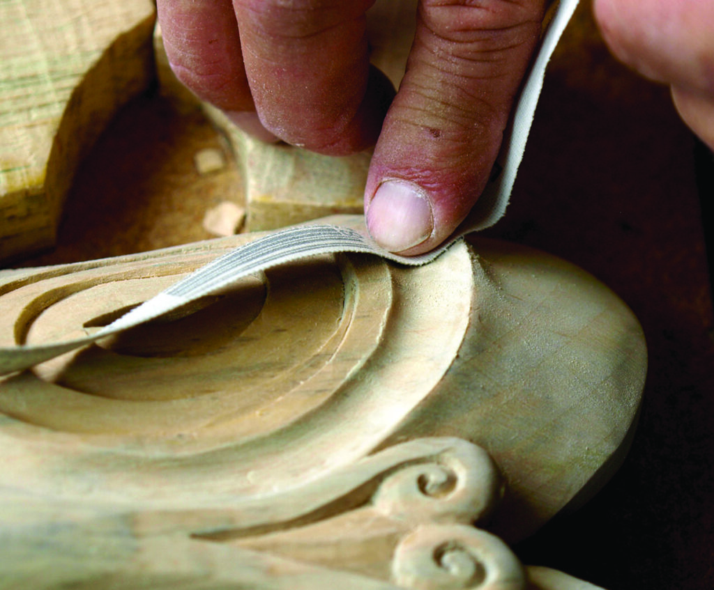 Craftsperson sanding a wooden instrument’s curved body
