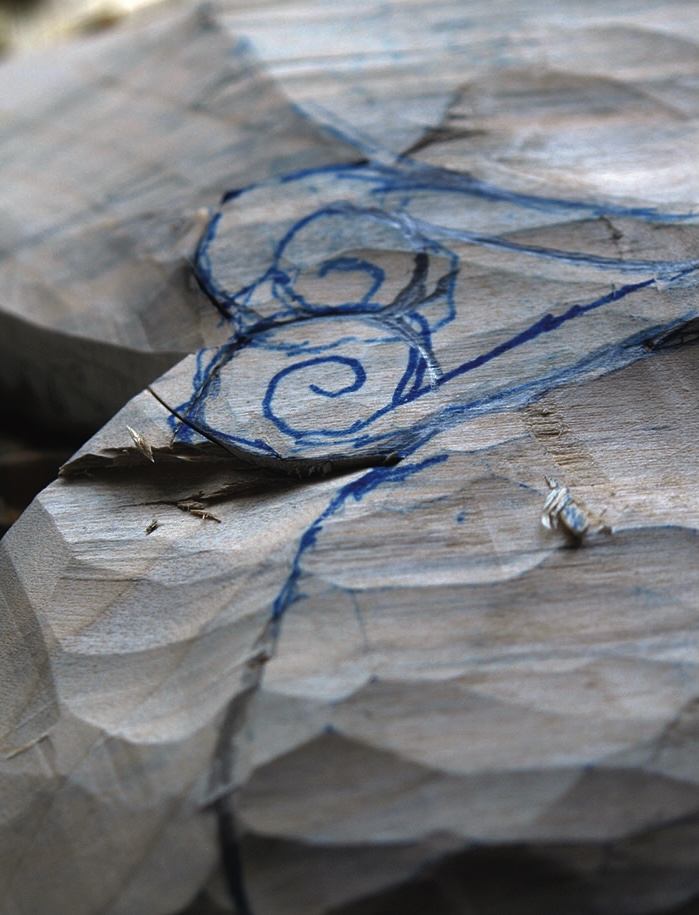 Blue spiral sketch on rough carved wood
