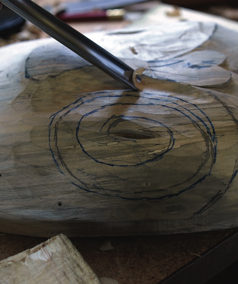 Gouge carving circular design into a wooden slab