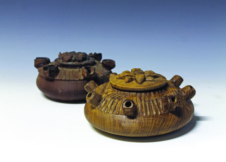 Two handcrafted wooden lidded pots on display.
