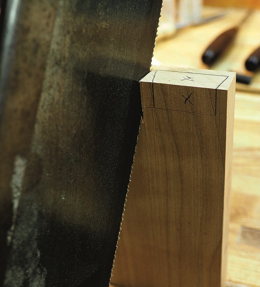 Handsaw cutting marked hardwood joint on workbench