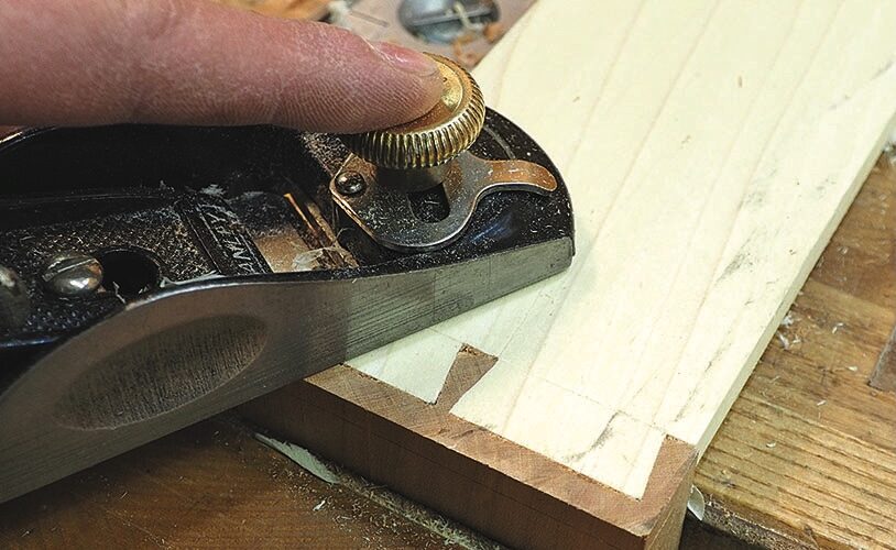 Hand planing a wooden board on a workbench