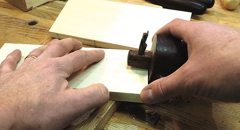 Woodworker hand-planing a small timber board at a bench