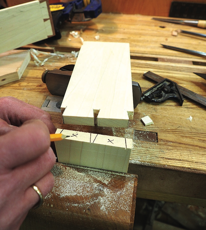 Woodworker marking dovetail joints on timber at workbench