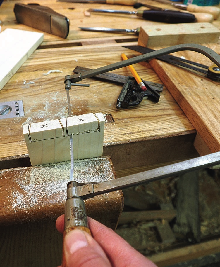Woodworker cutting marked timber with a coping saw