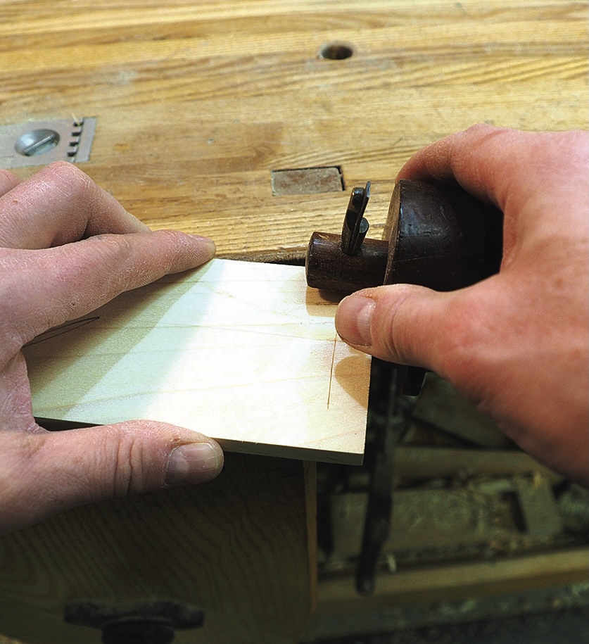Woodworker marking a board edge with a cutting gauge