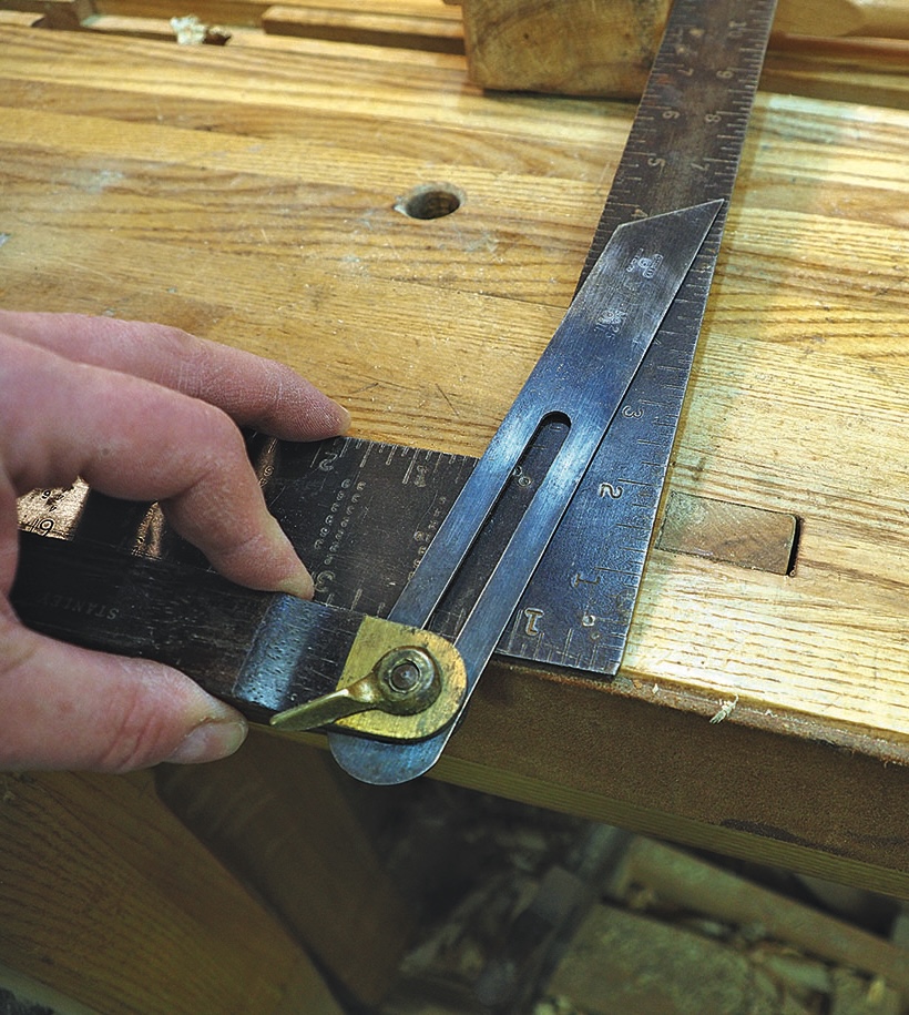 Hand adjusting steel square and bevel gauge on workbench