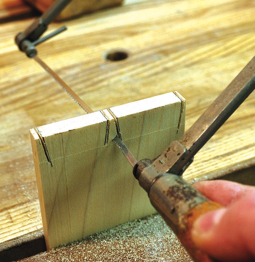 Craftsperson sawing a wooden joint with a coping saw