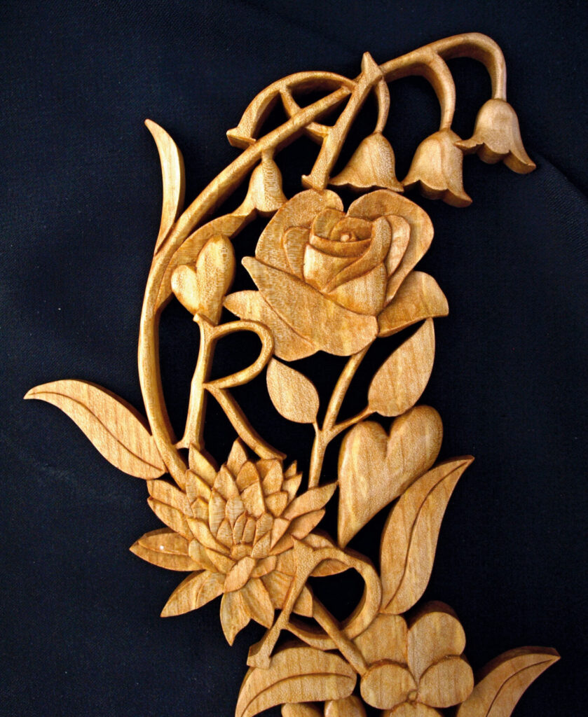 Intricate wooden carving with flowers and letters.
