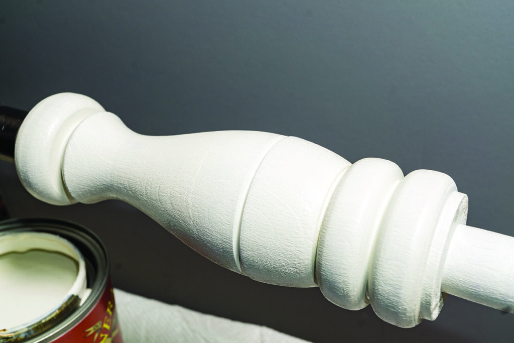 White-painted wooden spindle near open paint can.