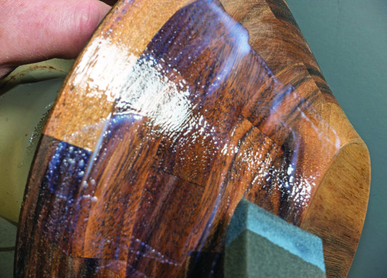 Applying finish to wooden bowl surface
