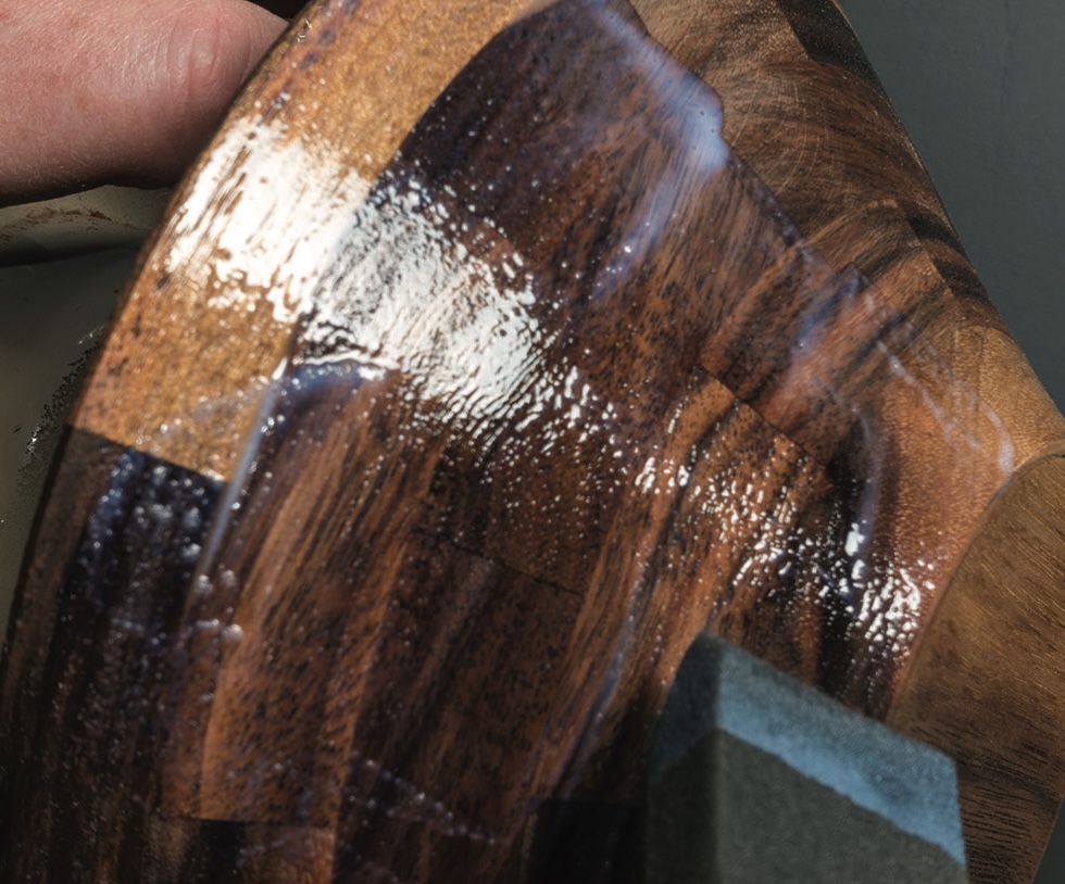 Applying oil to wooden bowl for finishing