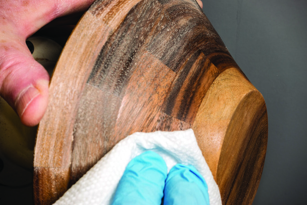 Person polishing wooden bowl with cloth.