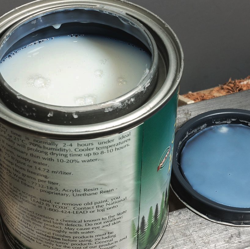 Open tin of white paint on wooden surface.