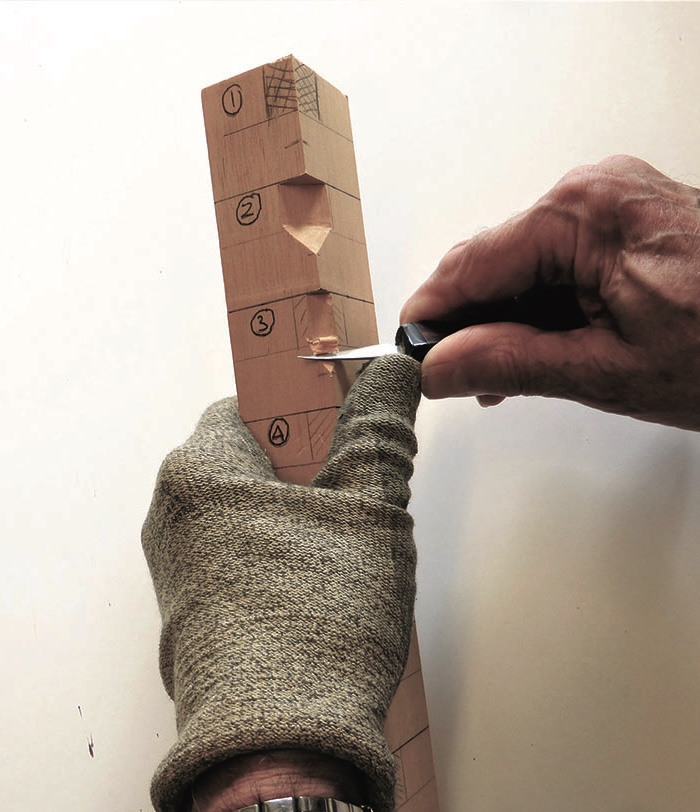 Person carving wood with a knife and glove.