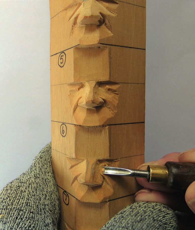Person carving wood faces with a chisel.