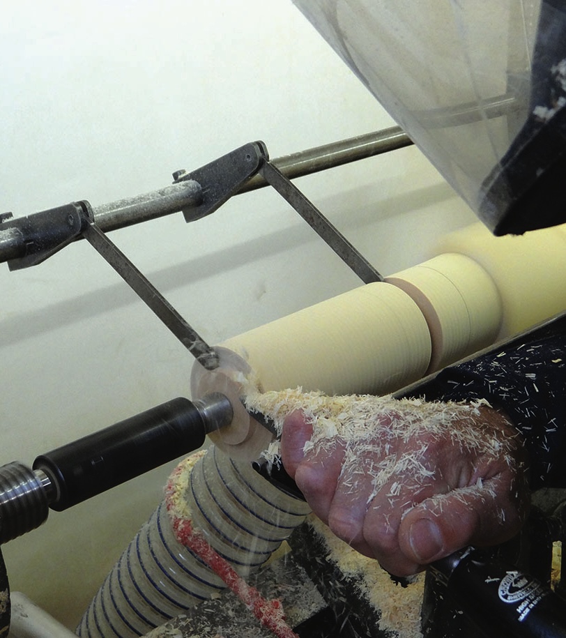 Woodturner shaping a spinning wooden piece on lathe