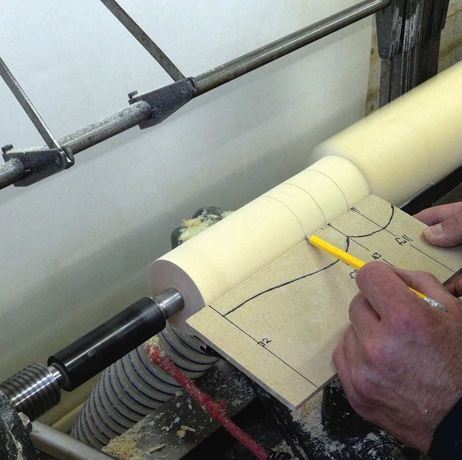 Woodworker marking template on lathe-mounted timber blank