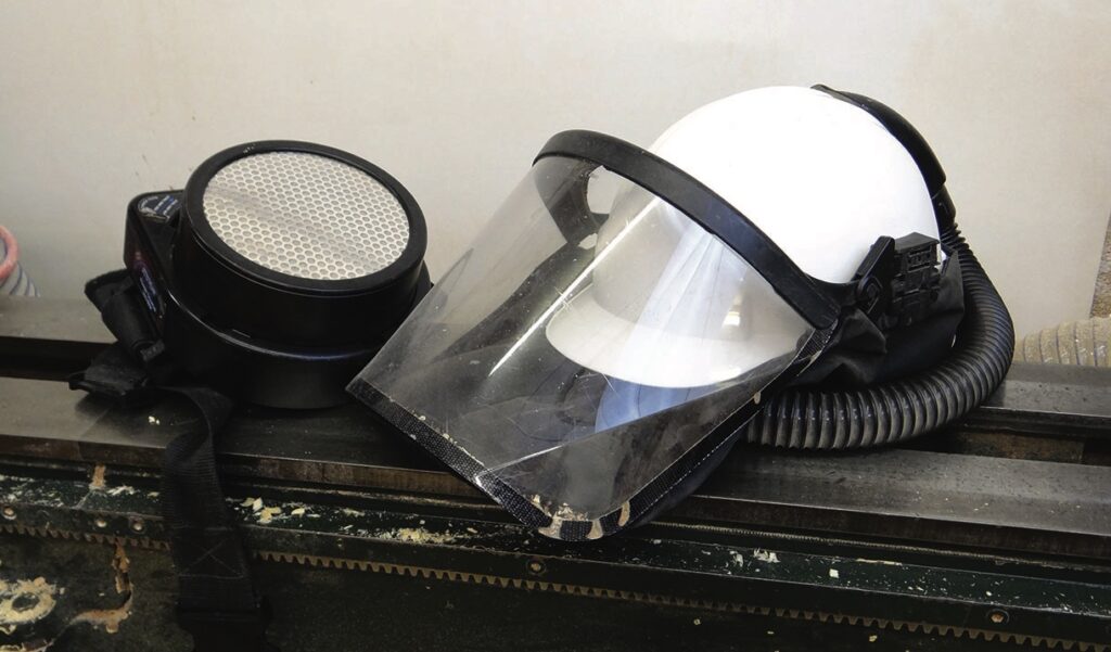 Protective respirator mask and face shield on workshop machinery