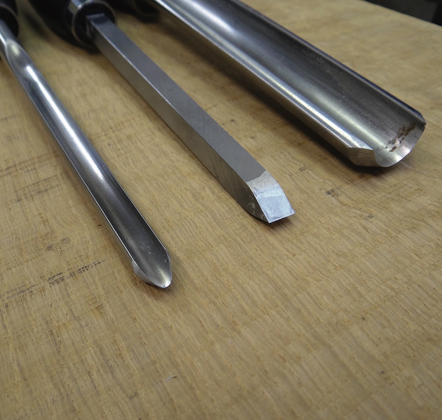 Three metal chisels on a wooden workbench
