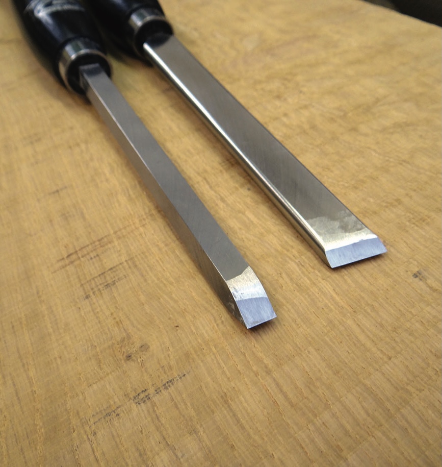 Two bevel-edged chisels on a wooden workbench