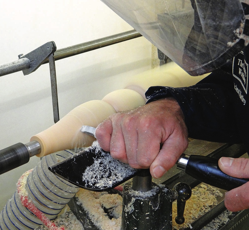 Woodturner shaping a wooden spindle on a lathe
