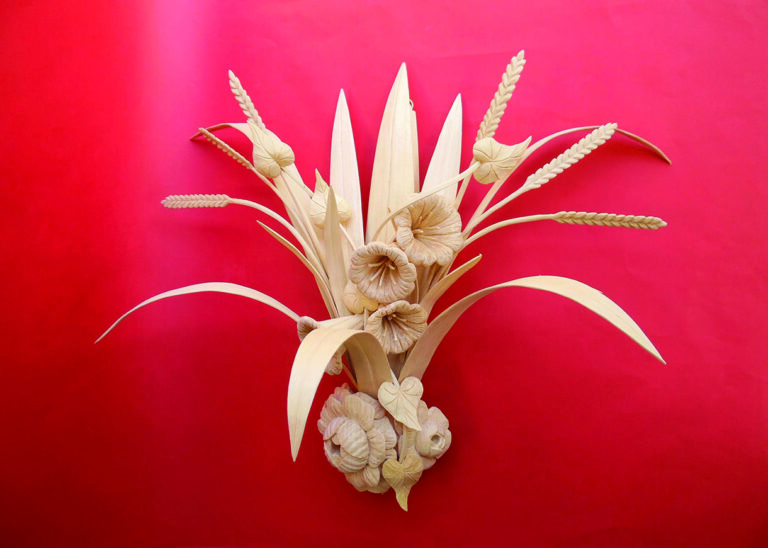 Intricate straw flower arrangement against vivid red background